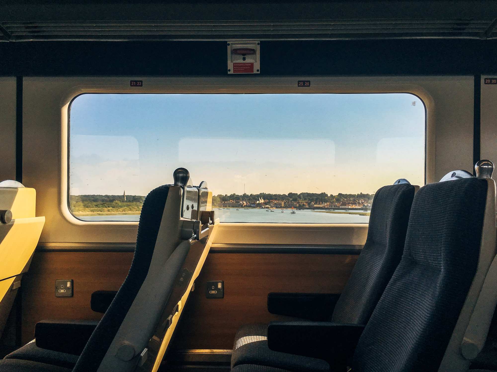 Passagerarfönster i ett tåg med utsikt över vatten och en stad.